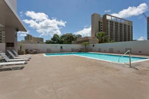 a swimming pool with lounge chairs next to a building at Royal Kuhio 1702 - Spacious Studio with Stunning Mountain City Views in the Heart of Waikiki! in Honolulu