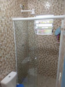 a bathroom with a glass shower with a toilet at Cantinho da Gigi in Peruíbe
