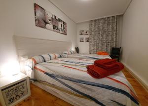 Un dormitorio con una cama con toallas rojas. en Apartamento Saioa, en Pamplona
