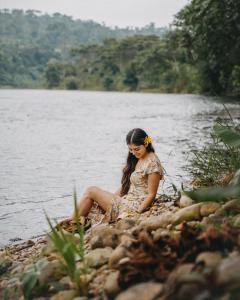 Arahuana Jungle Resort & Spa في تينا: امرأة جالسة على الصخور بجانب الماء