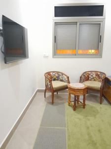 sala de estar con 2 sillas y TV en Appartement ennasr49, en Khenifra