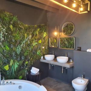 un bagno con tre lavandini e piante sul muro di BAITA MAORE luxury rooms & Spa a Làconi