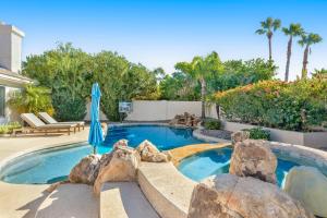 a swimming pool with rocks and an umbrella at Paradise in the Valley in Phoenix