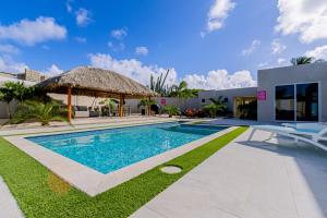 a villa with a swimming pool with a thatch roof at Turibana 50 G in Noord