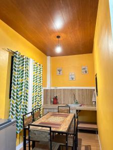 a dining room with yellow walls and a table and chairs at Vhauschild Transient Rooms -B in Alaminos
