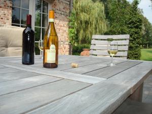 ヘールにあるB&B Hooglandhoeveの木製テーブルにワイン1本とグラス1杯
