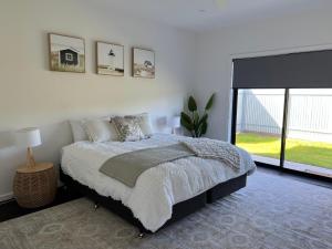 a bedroom with a bed and a large window at White Hut on Golflinks in Kingston South East