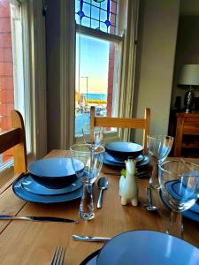 une table avec des assiettes et des verres sur une table avec une fenêtre dans l'établissement Harbour View Apartment, à Llandrillo-yn-Rhôs