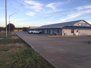 a building with a white car parked in a parking lot at Americas Best Value Inn Muskogee in Muskogee