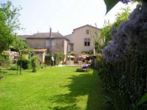 a green yard with a house and some flowers at Le Relais du Chapeau Rouge in Saint Loup Lamaire