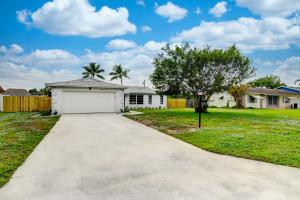 a driveway leading to a white garage in a yard at Just Remodeled! Close to All! 3 Miles to Beach!! 2 Miles From Airport! in West Palm Beach