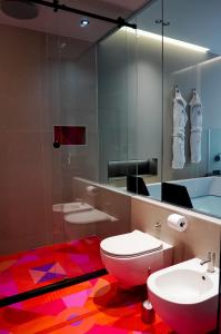 een badkamer met een toilet, een wastafel en een spiegel bij ZOE LUXURY SUITES in Catania
