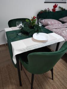 a table with a green chair and wine glasses on it at Divčibare Jezero apartman 25 in Divčibare