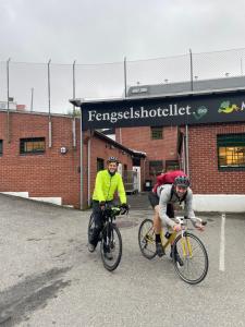 dwoje ludzi jeżdżących rowerami przed budynkiem w obiekcie Fengselshotellet w mieście Arendal
