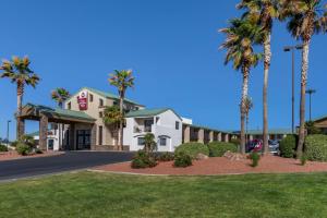 a hotel with palm trees in front of a building at Best Western Plus King's Inn and Suites in Kingman