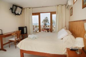 a bedroom with a bed with a desk and a television at Hotel Emancipador in Paracas