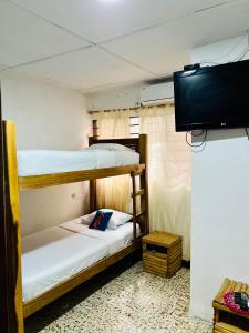 Pokój z 2 łóżkami piętrowymi i telewizorem z płaskim ekranem w obiekcie Hostal Liwa Kashi w mieście Ríohacha