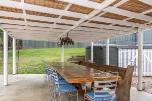 a wooden table and chairs under a pergola at The Estate Main House Byron Bay in Bangalow