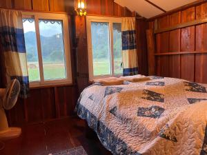 a bedroom with a bed in a room with windows at บ้านสวนวิวทุ่ง in Ban Mae Sap Nua