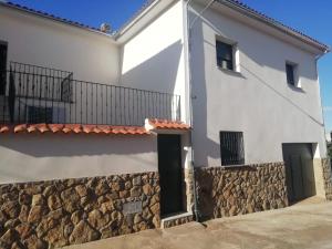 a white house with a stone wall at Casa Rural Feymar in Peraleda de San Román