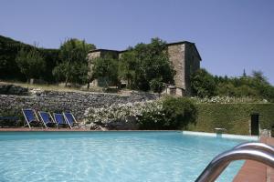 a swimming pool with two chairs and a stone wall at Badia a Coltibuono in Gaiole in Chianti