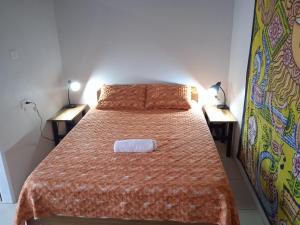 1 Schlafzimmer mit einem Bett mit einer orangefarbenen Tagesdecke und 2 Tischen in der Unterkunft Cabinas Negus in Uvita