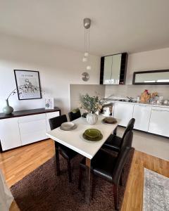 a white dining room table with black chairs in a kitchen at Apartman Floresta - In front of Japanese Garden, enchanting nature view, spotless and cozy in Vrnjačka Banja