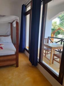 a bedroom with a bed and a table and a window at Majani Breeze in Nungwi