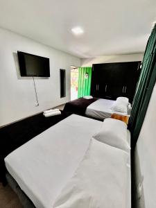 1 dormitorio con 2 camas y TV de pantalla plana en Yellow House, en Quimbaya
