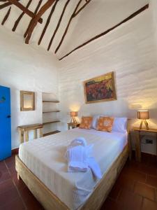 a bedroom with a white bed with a towel on it at El Principito Hospedaje in Barichara