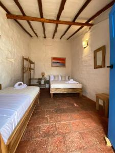 a room with two beds and a bench in it at El Principito Hospedaje in Barichara +37 photos