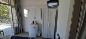a bedroom with a white cabinet and a tv on the wall at The Prospect of Howick Accommodation in Auckland