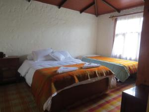 1 dormitorio con 2 camas y ventana en Rancho Santa Inés Completo, en Monguí