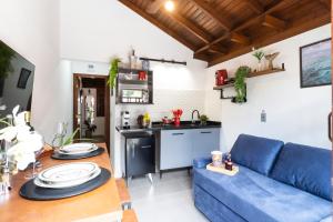 a living room with a blue couch and a kitchen at Flats Una's Corner - Novos - Ar Condicionado in Barra do Una