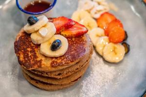 a stack of pancakes with fruit on a plate at Refugio Surf Lodge in Tamarindo