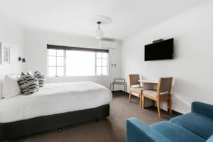 1 dormitorio con cama, mesa y sofá en The Mission Belle Motel en Mount Maunganui