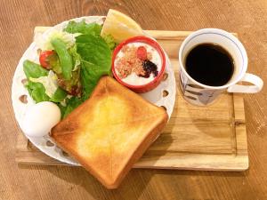 un plato con un sándwich y una ensalada y una taza de café en Yadocafe Chelsea's Rainbow B&B en Osaka