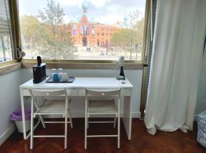a white desk with two chairs in front of a window at L83 - rooms and apartments in Lisbon
