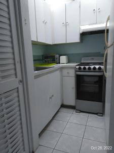 - une cuisine avec des placards blancs et une cuisinière dans l'établissement Irresistible View-Mobay Club 1408, à Montego Bay
