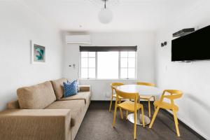 a living room with a couch and a table and chairs at The Mission Belle Motel in Mount Maunganui