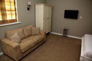 a living room with a couch and a tv at The Bull Inn Lodges in Tenterden