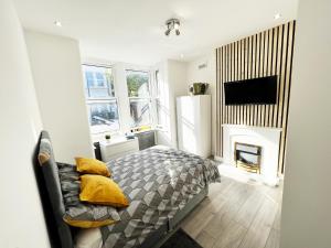ein Schlafzimmer mit einem Bett mit gelben Kissen und einem Kamin in der Unterkunft Minet Gardens - Centrally located Apartment - Rm 1 in London