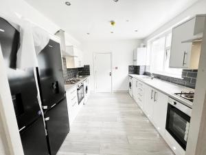 ロンドンにあるMinet Gardens - Centrally located Apartment - Rm 1のキッチン(白いキャビネット、黒の電化製品付)