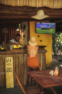 Una donna seduta su uno sgabello davanti a un bar di Pousada Pouso da Maré a Ilha de Boipeba