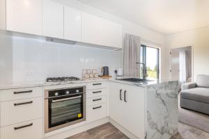 a kitchen with white cabinets and a stove top oven at Fairway Cottages in Rotorua