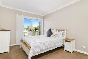 a white bedroom with a bed and a window at Cathie 29 in Port Macquarie