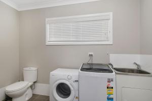 a bathroom with a washing machine and a sink at Cathie 29 in Port Macquarie