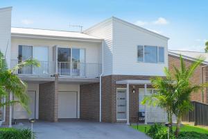 a large white house with a balcony and palm trees at Cathie 29 in Port Macquarie