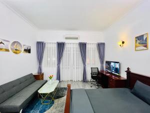 ein Wohnzimmer mit einem Sofa und einem TV in der Unterkunft MINA HOUSE Airport Apartment in Ho-Chi-Minh-Stadt