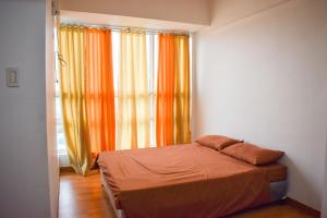 a bedroom with an orange bed and a window at The Boni Tower by RSPL Manila City Center in Manila +30 photos